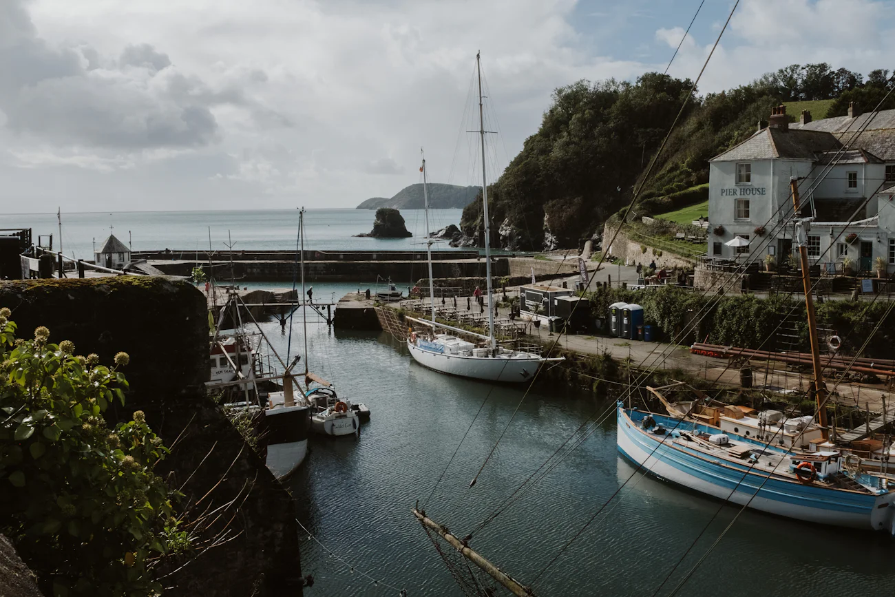 Small boats moored in a harbour below a white house